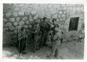 Five paratroopers have a tea break on a cobbled street in Palestine.