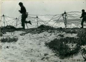 Two men of 1st Airborne Division run along a beach in training for the sea landings of Operation Torch. 