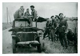 Commandos of 1st Special Service Brigade with captured Germans  on and around a military vehicle near drop zone N.