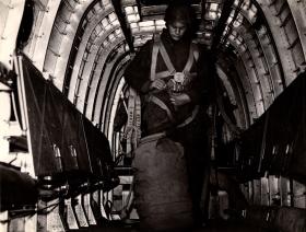Paratrooper inside aircraft with kit bag