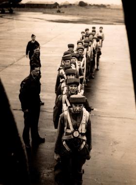 Pupils in line boarding a aircraft wearing sorbo helmets