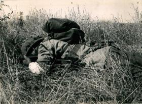 Paratrooper takes cover in some long grass while training, North Africa, 1943