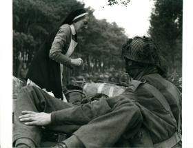 A Dutch nurse giving first aid to a wounded paratrooper. 