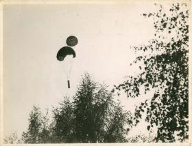 Resupply container being parachuted to soldiers on the ground.