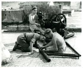 Drivers and batman master the intricacies of a German Flak gun captured in southern France.