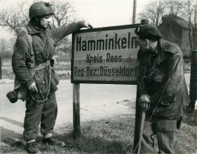 Two British airborne men by the sign for Hamminkeln the day they took the town.