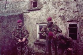 A patrol of 1 PARA stand in front of an old stone building.