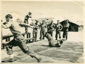 Troops practise parachute rolls on mats as part of synthetic training.
