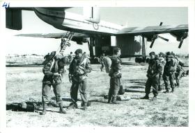 A stick of Paratroopers adjust their equipment before emplaning a Blackburn Beverley aircraft.