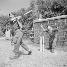 Members of 6th Airborne Divisional Signals play cricket in Normandy, 31 July 1944.