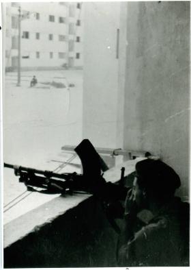 A member of the Parachute Regiment aims his gun out of a window in El Gamil.