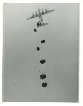 Hastings aircraft dropping arms and equipment by parachute to men on the ground.