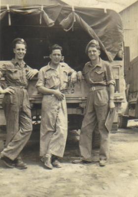 Three soldiers relaxing by a vehicle