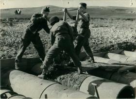 Three men of 1st Parachute Squadron RE preparing a road with concrete.