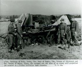 Four paratroopers stand with a burned out Hotchkiss tank chassis.