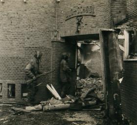 Two paratroopers with Sten guns enter a destroyed school.