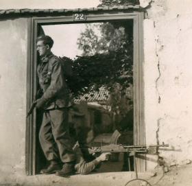 Two paratroopers take up position in the doorway of a building.