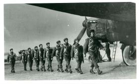 A stick of parachutists march in a line to emplane a Whitley aircraft.