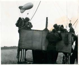 Parachute trainees climb into a balloon cage prior to a training jump.