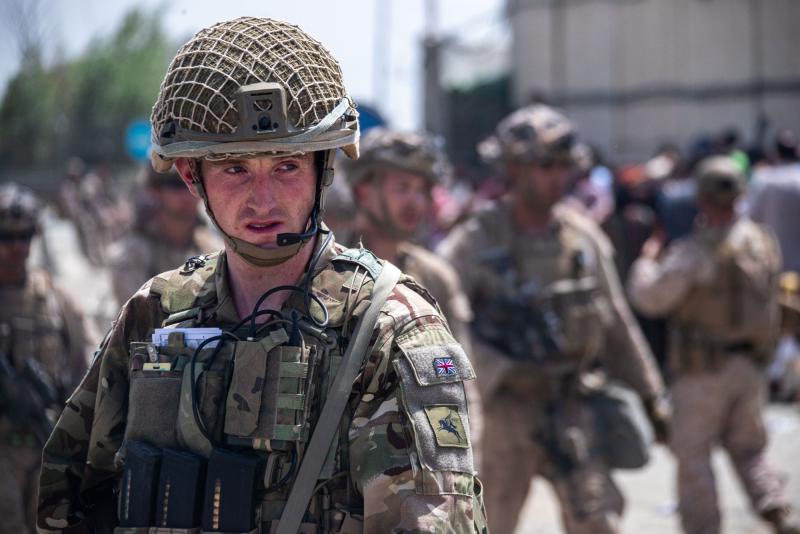 A colour photo of paratrooper standing in front of some US Marines, Kabul airport, August 2021
