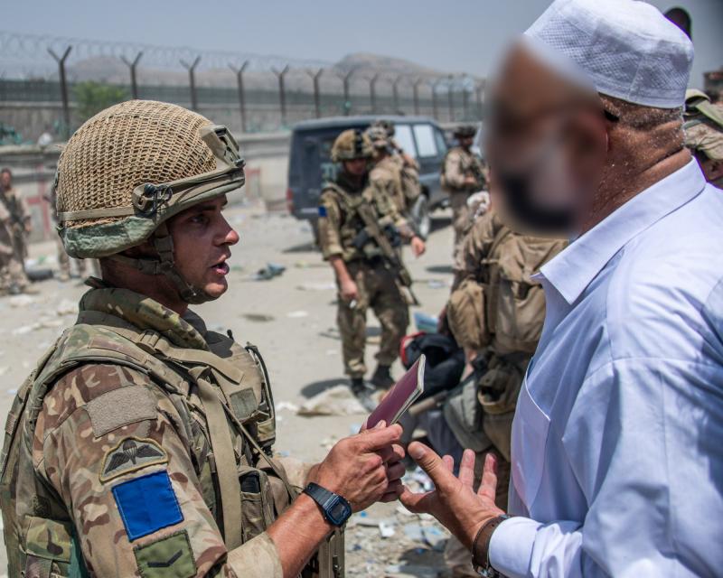 Colour photo of a soldier from 2 PARA talking with an Afghan, Kabul airport, August, 2021