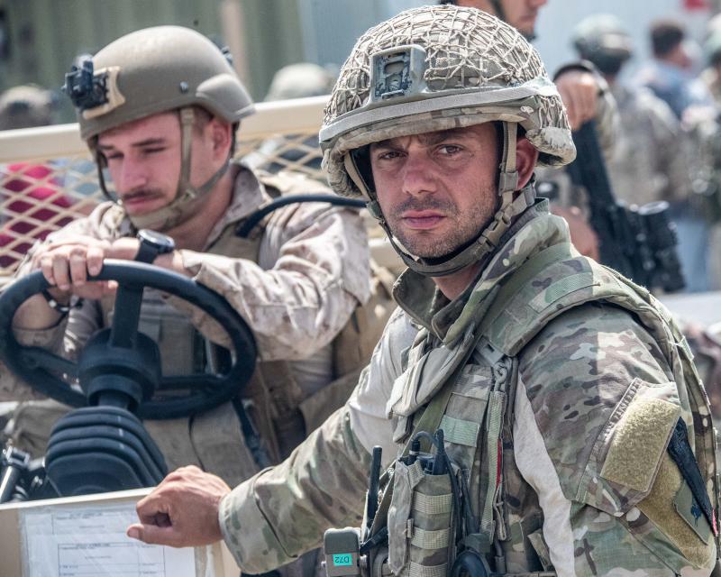 Colour image of a soldier standing next to a US Marine seated in a vehicle, Kabul airport, August 2021