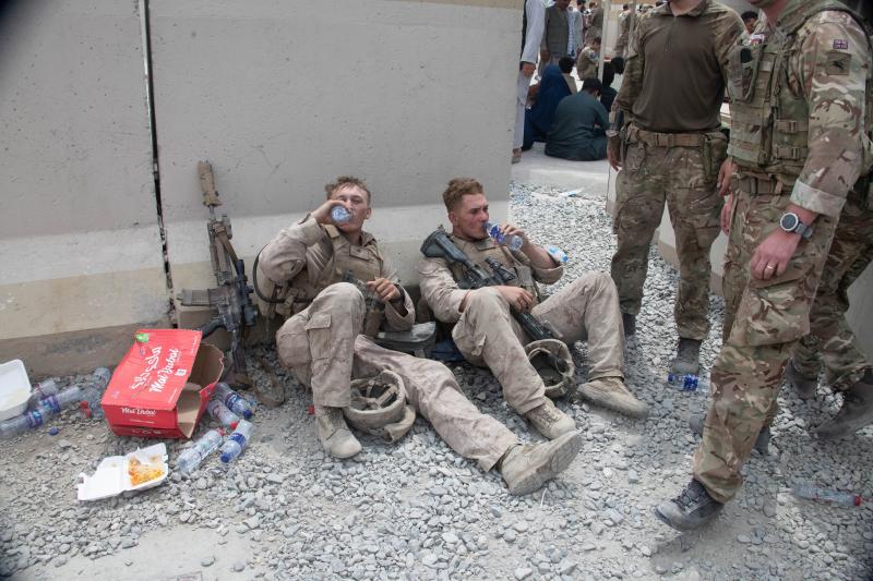 A colour photo of two US Marines drinking water whilst sat on the floor water whilst members of 16 Air Assault Brigade standby, Kabul airport, August 2021