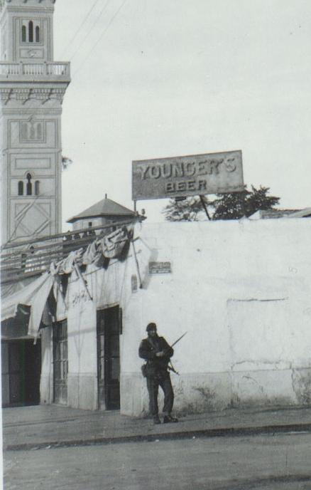 OS 1952-01-21 Cpl Smith, 3 Para, patrols under familiar beer sign, Ismailia,Egypt