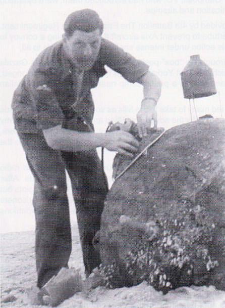 Major David Breese attaches an explosive charge to an old sea mine