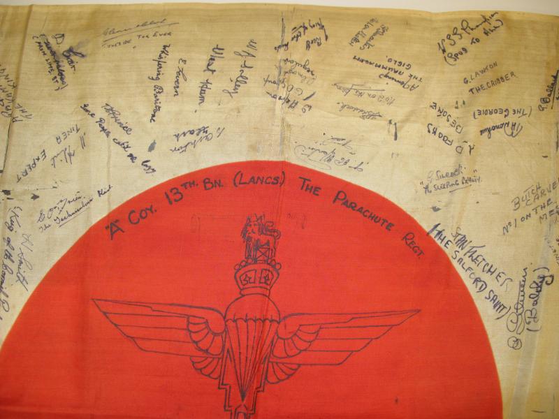 Close up top down view of a trophy Japanese flag signed by men of the 13th Lancashire Parachute Battalion