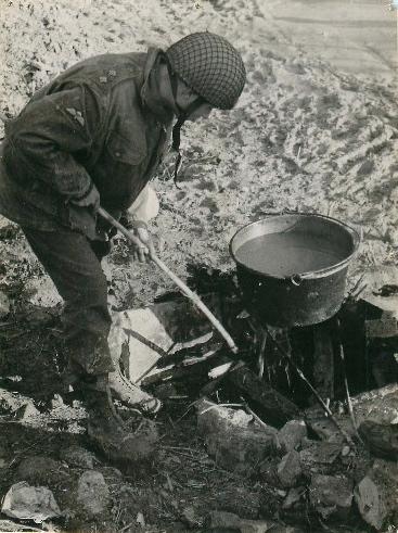 Lieutenant Stanning makes soup on a fire among rocks.