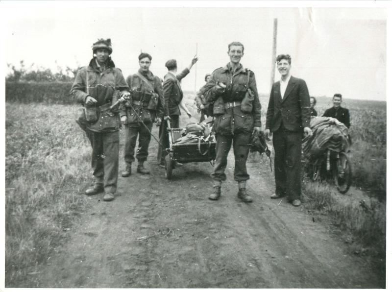 Paratroopers pose with Dutch civilians on a track between fields.