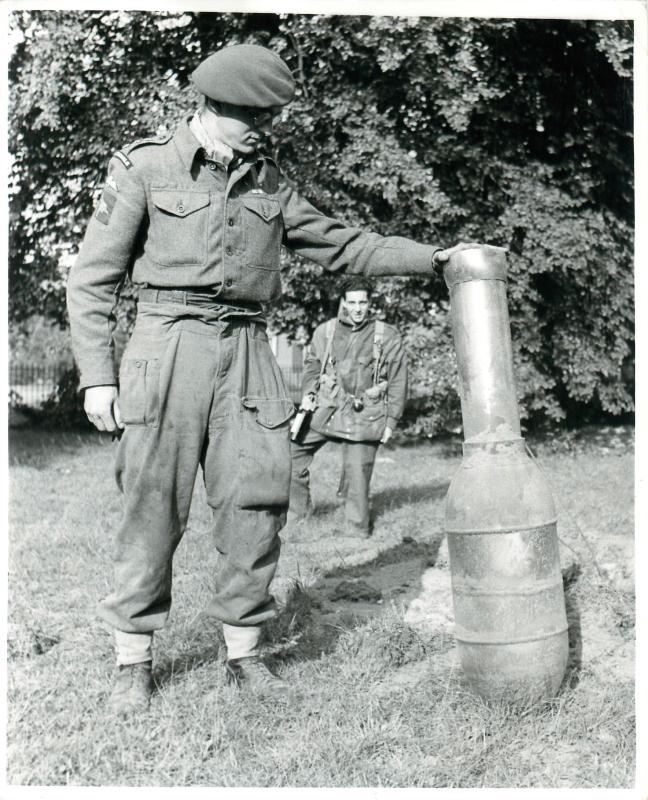 Airborne Signaller holds German unexploded German rocket in Hartenstein Hotel grounds.
