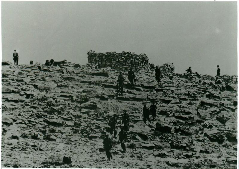 Men advancing to contact on rocky terrain.