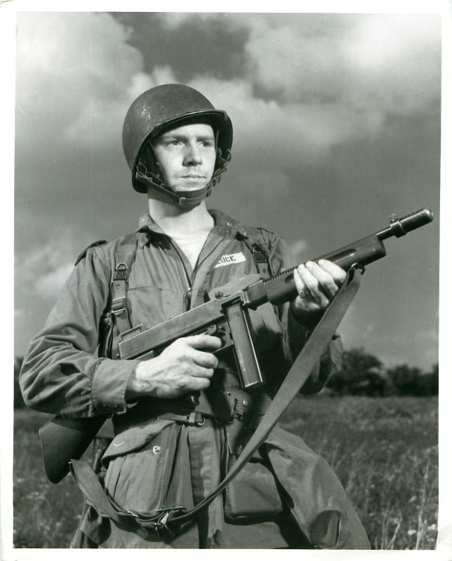 A US paratrooper stands with rifle.