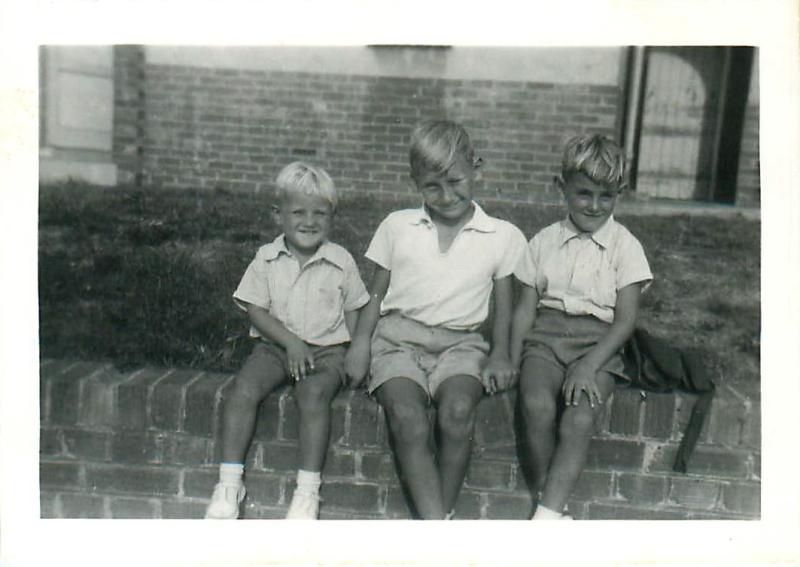 Steve Prior (right) and two of his brothers sit on a wall.