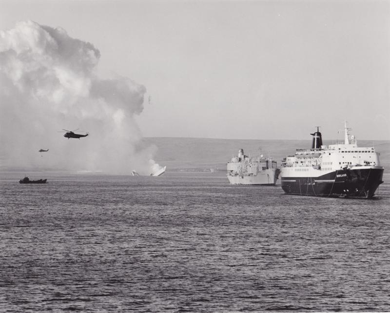 MV Norland in San Carlos Bay as HMS Antelope sinks in the background, Falklands, May 1982