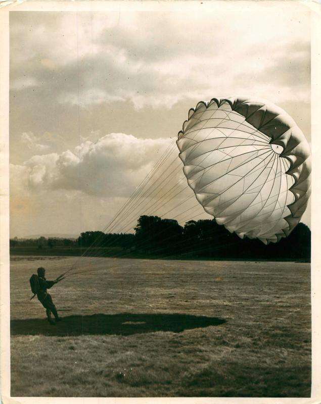 Parachute instructor lands and starts to collapse his parachute.