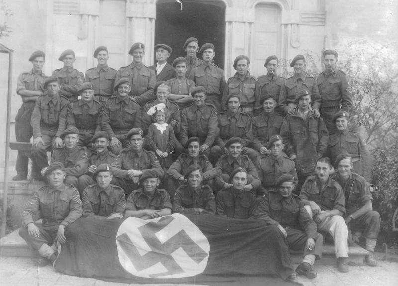 Group photo of 1st Airlanding Brigade Signal Section posing with a captured flag, Italy, October 1943