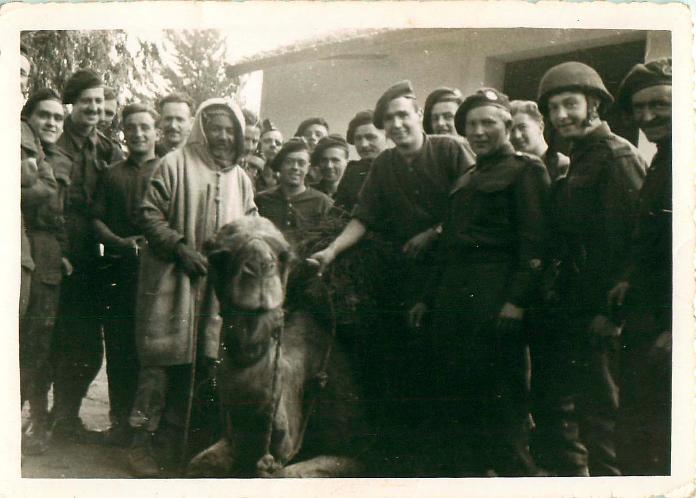 Soldiers pose with a camel and a local man.
