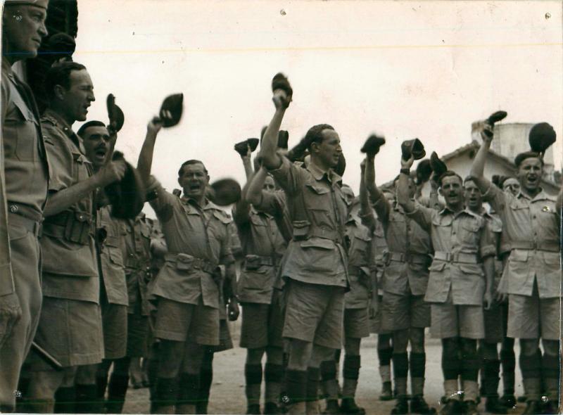 Men of 1st Parachute Brigade raise their berets in the air during General Eisenhower's visit.