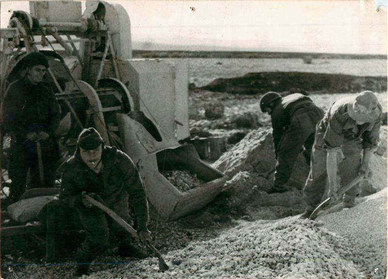 Four men of 1st Parachute Squadron RE use shovels to repair a road.