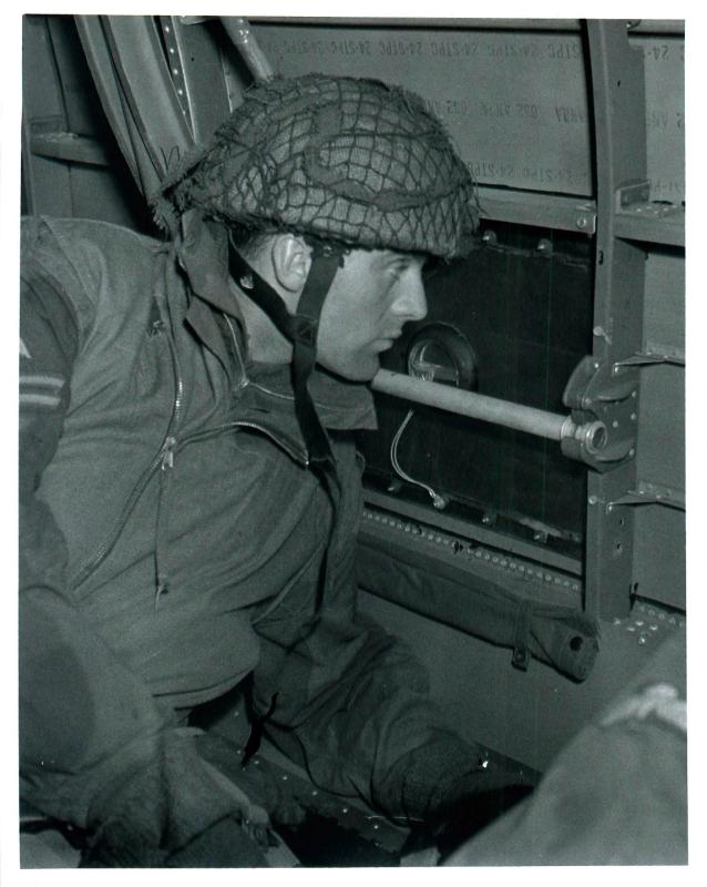 Paratrooper looks out a Douglas Dakota aircraft window for briefed landmarks on approaching the drop zone.