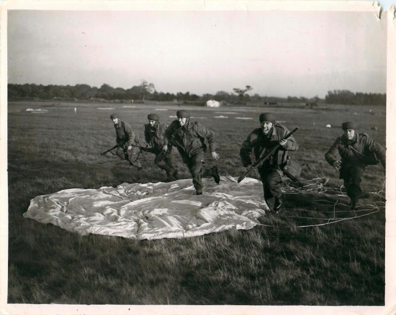 Posed photo of paratroopers ready for action after discarded their parachutes.